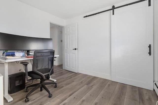 office with a barn door, light wood-type flooring, and a baseboard radiator