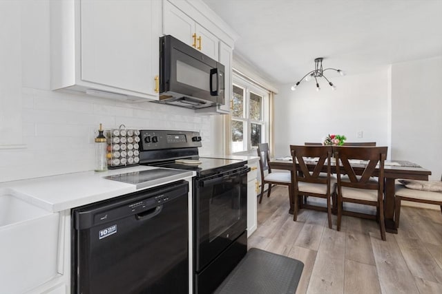 kitchen with backsplash, light hardwood / wood-style flooring, white cabinets, and black appliances