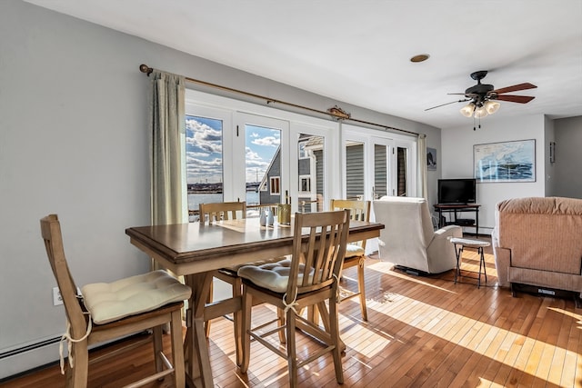 dining area featuring a baseboard radiator, wood-type flooring, and ceiling fan