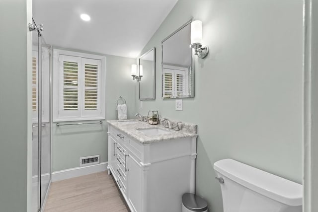 9 Oak St, Wayland, MA 01778 - bathroom featuring double vanity, toilet, wood finished floors, baseboards, and an enclosed shower