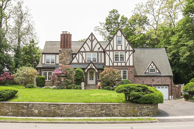 493 Salisbury St, Worcester, MA 01609 - tudor house featuring asphalt driveway, a front lawn, a chimney, an attached garage, and stucco siding
