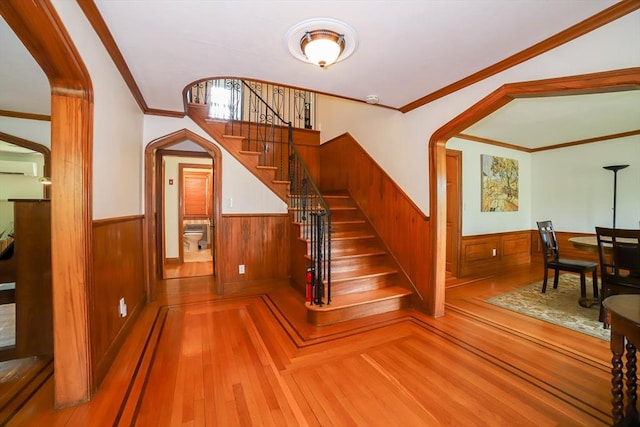 493 Salisbury St, Worcester, MA 01609 - staircase with wainscoting, wood finished floors, arched walkways, a wall mounted air conditioner, and wooden walls