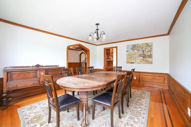 493 Salisbury St, Worcester, MA 01609 - dining area featuring a chandelier, light wood finished floors, wainscoting, crown molding, and arched walkways