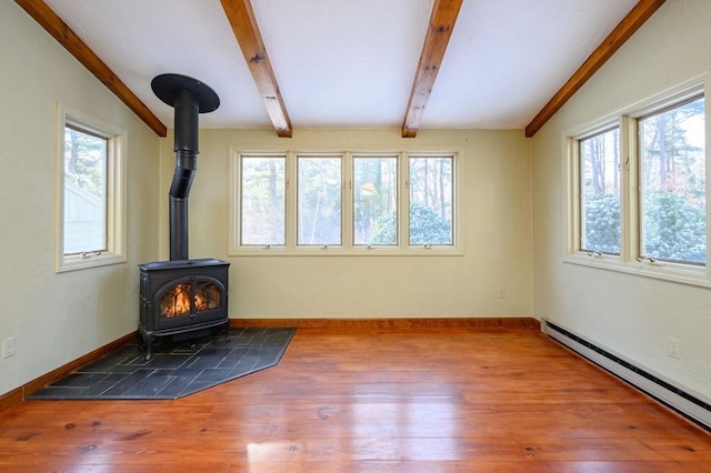 unfurnished living room with wood-type flooring, lofted ceiling with beams, a wood stove, and a baseboard heating unit