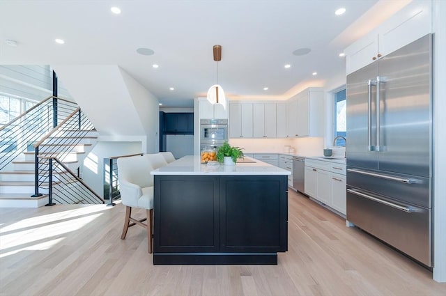 kitchen with stainless steel appliances, a kitchen island, hanging light fixtures, and white cabinets