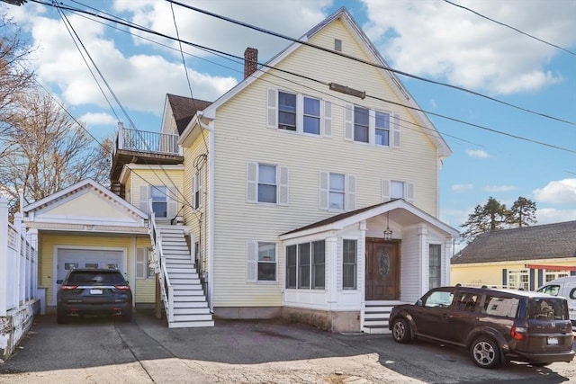 view of front of house featuring a chimney, stairs, entry steps, driveway, and a garage