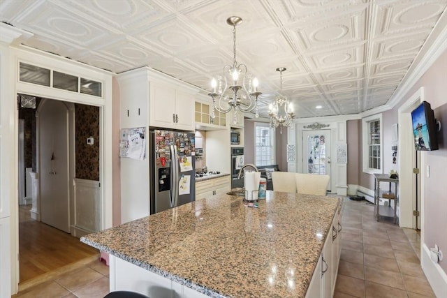 kitchen with a center island with sink, an ornate ceiling, a chandelier, white cabinetry, and stainless steel refrigerator with ice dispenser
