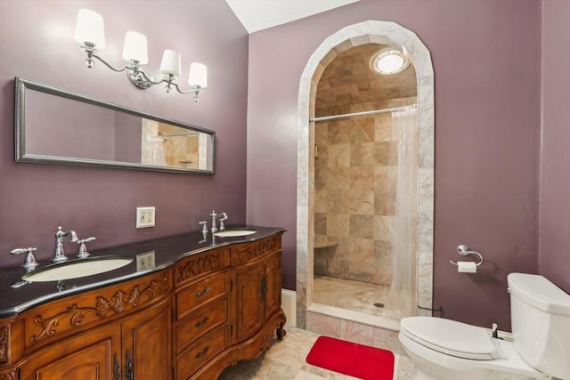 bathroom with double vanity, toilet, tiled shower, and a sink