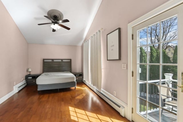 bedroom featuring a baseboard heating unit, vaulted ceiling, wood finished floors, and baseboards