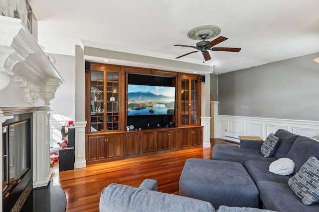 living area featuring wainscoting, a baseboard radiator, a ceiling fan, and wood finished floors