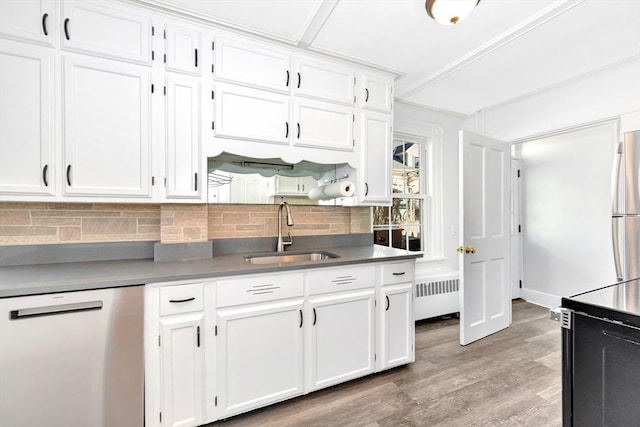 kitchen featuring dishwashing machine, radiator heating unit, white cabinetry, tasteful backsplash, and sink