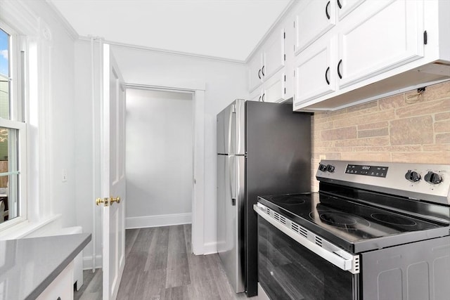 kitchen with crown molding, stainless steel electric range, white cabinets, light hardwood / wood-style flooring, and backsplash