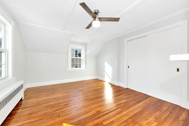 additional living space featuring ceiling fan, radiator heating unit, hardwood / wood-style floors, and lofted ceiling