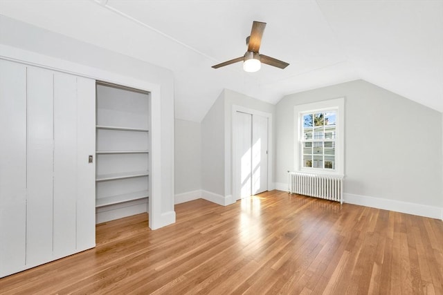 bonus room featuring built in shelves, radiator heating unit, lofted ceiling, and light wood-type flooring