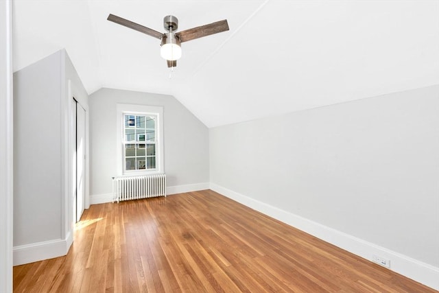 additional living space with ceiling fan, light wood-type flooring, radiator, and vaulted ceiling