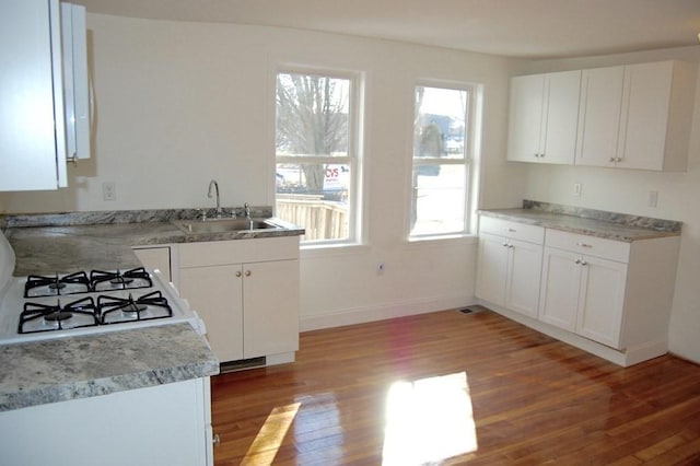 kitchen with baseboards, white cabinets, a sink, and light wood finished floors