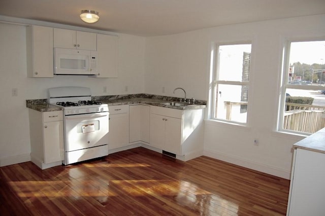 kitchen featuring white appliances, dark wood finished floors, a wealth of natural light, and a sink
