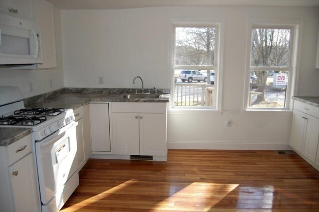 kitchen featuring white appliances, a healthy amount of sunlight, a sink, and wood finished floors