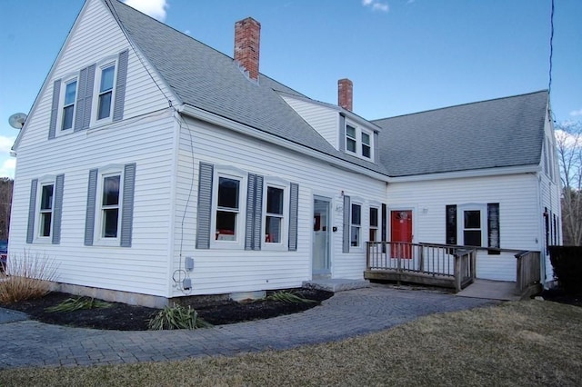 view of front of property featuring a deck, roof with shingles, and a chimney