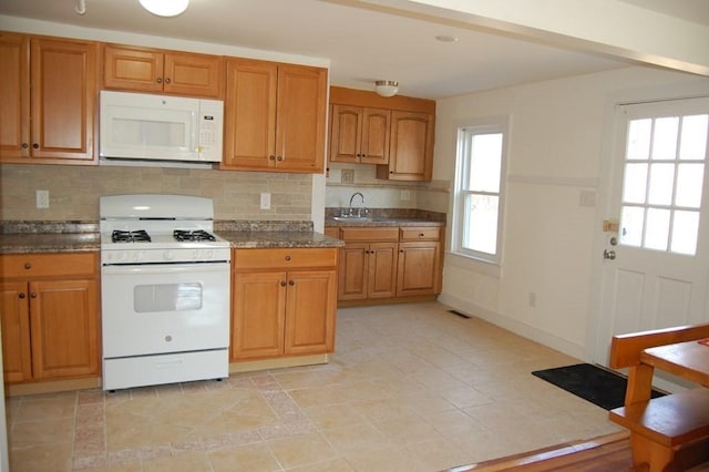 kitchen with white appliances, a sink, visible vents, decorative backsplash, and brown cabinetry