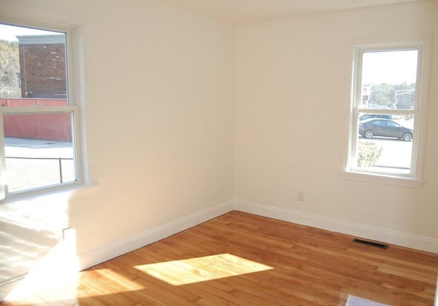 unfurnished room featuring visible vents, baseboards, and wood finished floors