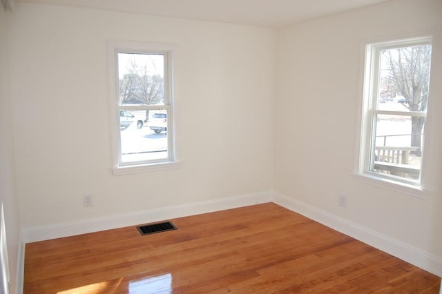 unfurnished room featuring a wealth of natural light, visible vents, and light wood finished floors