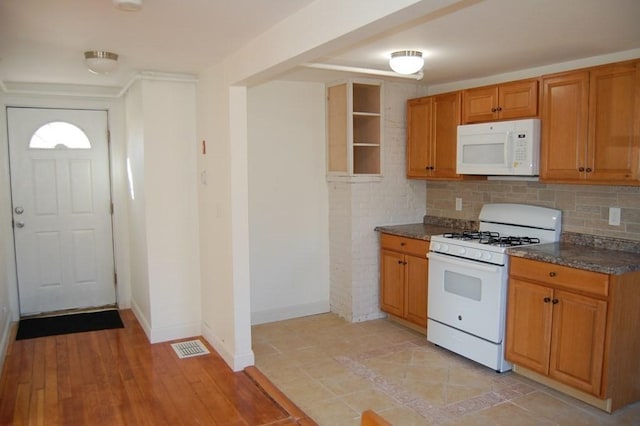 kitchen with brown cabinetry, white appliances, baseboards, and decorative backsplash