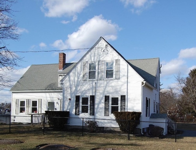 back of property featuring a fenced front yard, a chimney, and a shingled roof