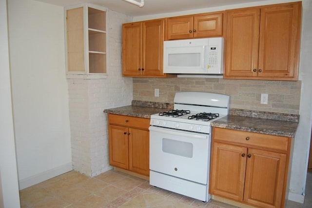 kitchen featuring white appliances, brown cabinetry, dark stone countertops, and backsplash