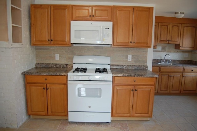kitchen featuring white appliances, a sink, and brown cabinets