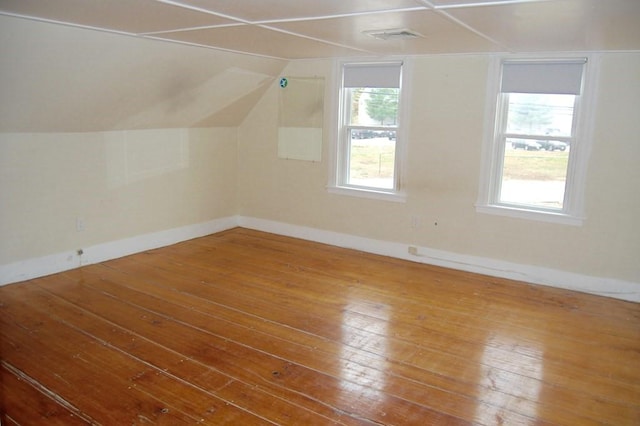 additional living space featuring lofted ceiling, wood-type flooring, visible vents, and plenty of natural light