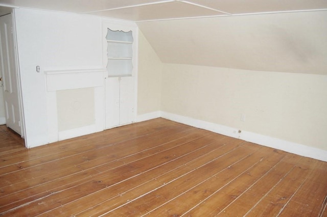 additional living space featuring baseboards, vaulted ceiling, and hardwood / wood-style floors