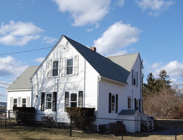 view of front of house with roof with shingles, a fenced front yard, and a chimney