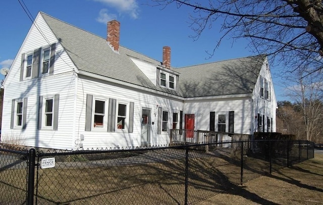 view of front facade with roof with shingles, a chimney, and a fenced front yard