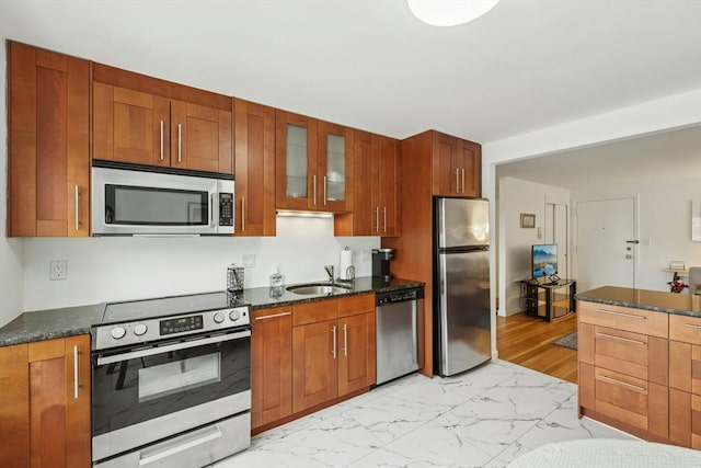 128 Pleasant St Unit 407, Arlington, MA 02476 - kitchen with stainless steel appliances, a sink, glass insert cabinets, light marble finish floors, and brown cabinets