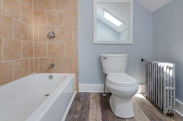 17 Harrison St, New Bedford, MA 02740 - full bathroom with radiator, wood finished floors, baseboards, toilet, and a skylight