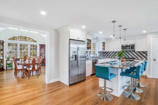 8 Dylans, Falmouth, MA 02536 - kitchen featuring stainless steel appliances, backsplash, white cabinetry, glass insert cabinets, and light wood-style floors