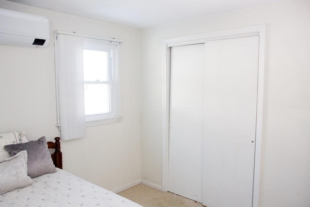 bedroom with a wall mounted AC, carpet flooring, a closet, and baseboards