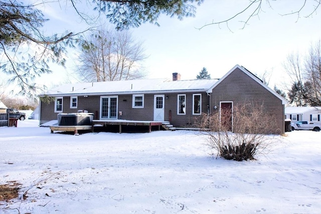 snow covered house featuring a chimney and a wooden deck