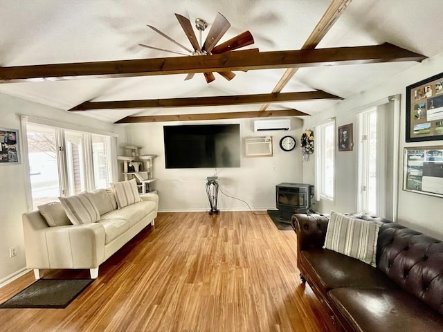 living room with vaulted ceiling with beams, hardwood / wood-style floors, plenty of natural light, a wall mounted AC, and a wood stove