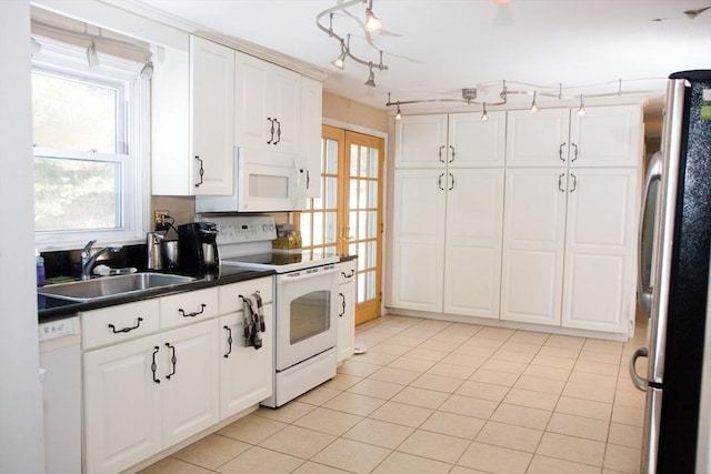 kitchen featuring dark countertops, white cabinetry, a sink, light tile patterned flooring, and white appliances