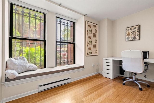 office area featuring baseboard heating, wood finished floors, and baseboards
