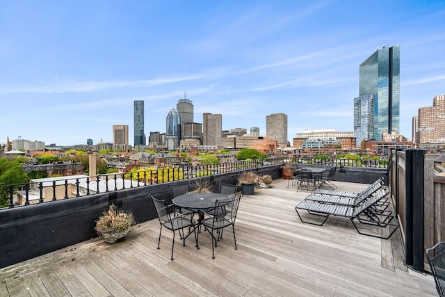 wooden deck featuring outdoor dining area and a skyline view