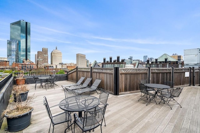 wooden terrace with outdoor dining area and a skyline view
