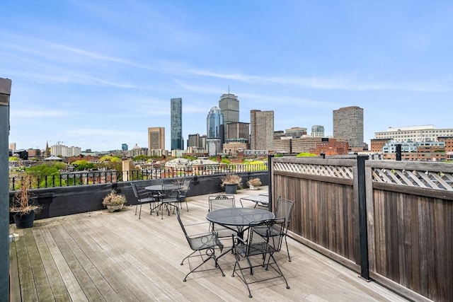 deck featuring outdoor dining space and a skyline view