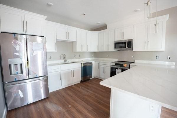 kitchen featuring white cabinets, stainless steel appliances, sink, hanging light fixtures, and dark hardwood / wood-style floors