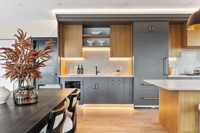 kitchen featuring sink, backsplash, gray cabinets, and light hardwood / wood-style floors