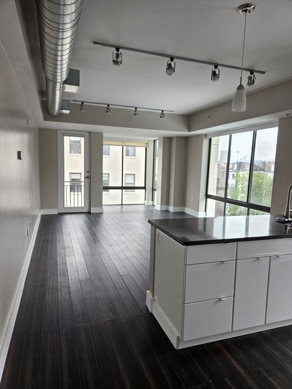 kitchen with open floor plan, dark countertops, healthy amount of natural light, and baseboards