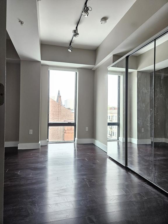 empty room with plenty of natural light, fire sprinkler in ceiling, baseboards, and a smoke detector