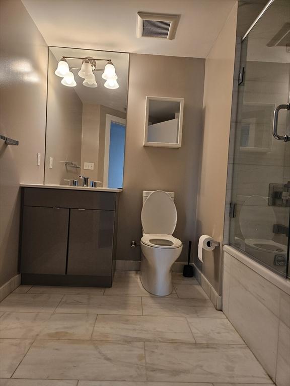 bathroom with a shower with door, baseboards, marble look tiles, and toilet